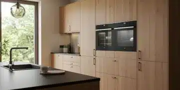 Modern minimalist kitchen with warm wood cabinets and smart appliances, bathed in natural light.