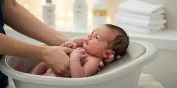 Newborn baby safely and gently bathed in a baby tub by a parent's hands.