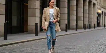 Woman in oversized beige blazer, graphic tee, distressed jeans, and chunky sneakers walking in urban setting